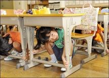 Des enfants se cachent sous une table lors d'un exercice anti-sismique, en septembre 2008.(photo archive AFP)