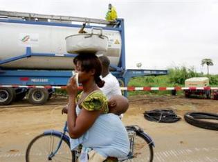 Une femme et son enfant passent à proximité d’employés d’une firme qui tentent de dépolluer la zone touchée par le rejet des déchets toxiques du Probo koala, près d’Abidjan.