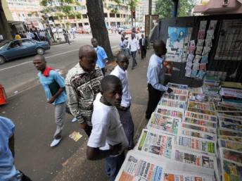 Des hommes devant un étalage de journaux, dans les rues d'Abidjan en 2008. KAMBOU SIA / AFP