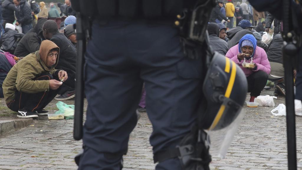 Des migrants mangent devant un cordon de policiers à Calais, le 24 octobre 2014. REUTERS/Pascal Rossignol